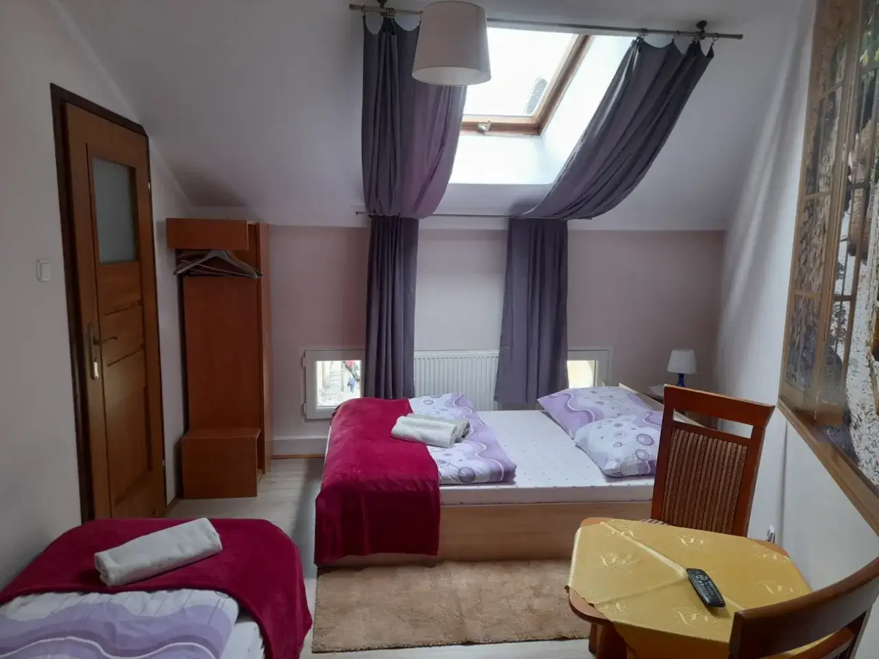 Pokój z dwoma łóżkami, szafą i stolikiem. Idealne miejsce, by sprawdzić, ile kosztuje nocleg w Krakowie.