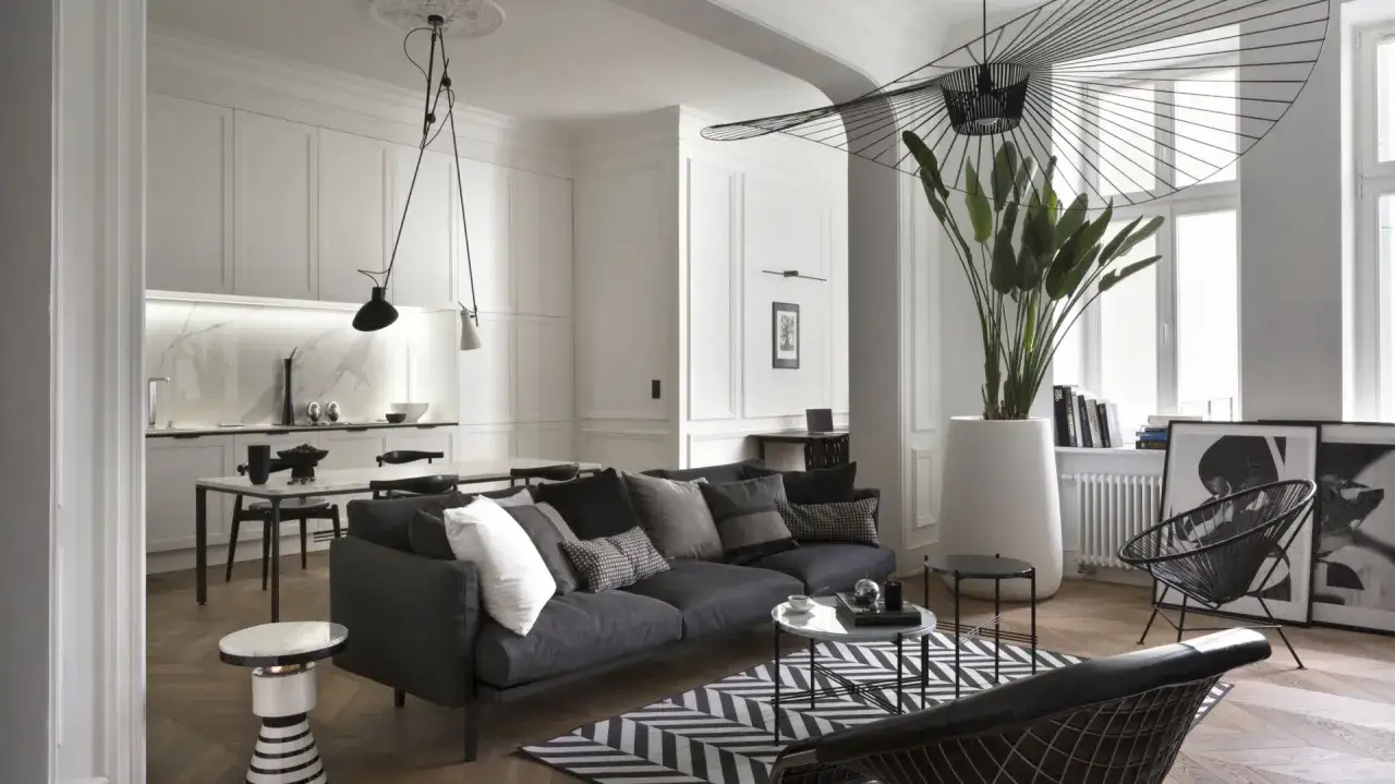 Eleganckie mieszkanie w stylu paryskim z ciemną sofą, geometryczną ławą i stylowym oświetleniem.