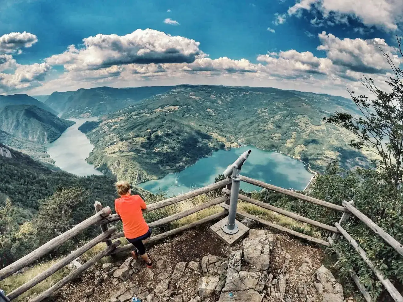 Widok z punktu widokowego w parku narodowym Tara. Kobieta w pomarańczowej bluzce podziwia malowniczą dolinę rzeki i g&oacute;ry.
