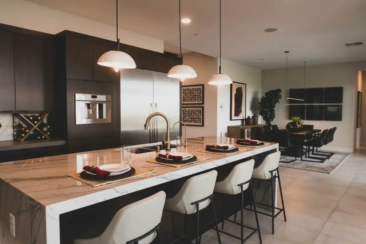 Elegante mueble cocina isla con encimera de mármol, taburetes y electrodomésticos modernos.