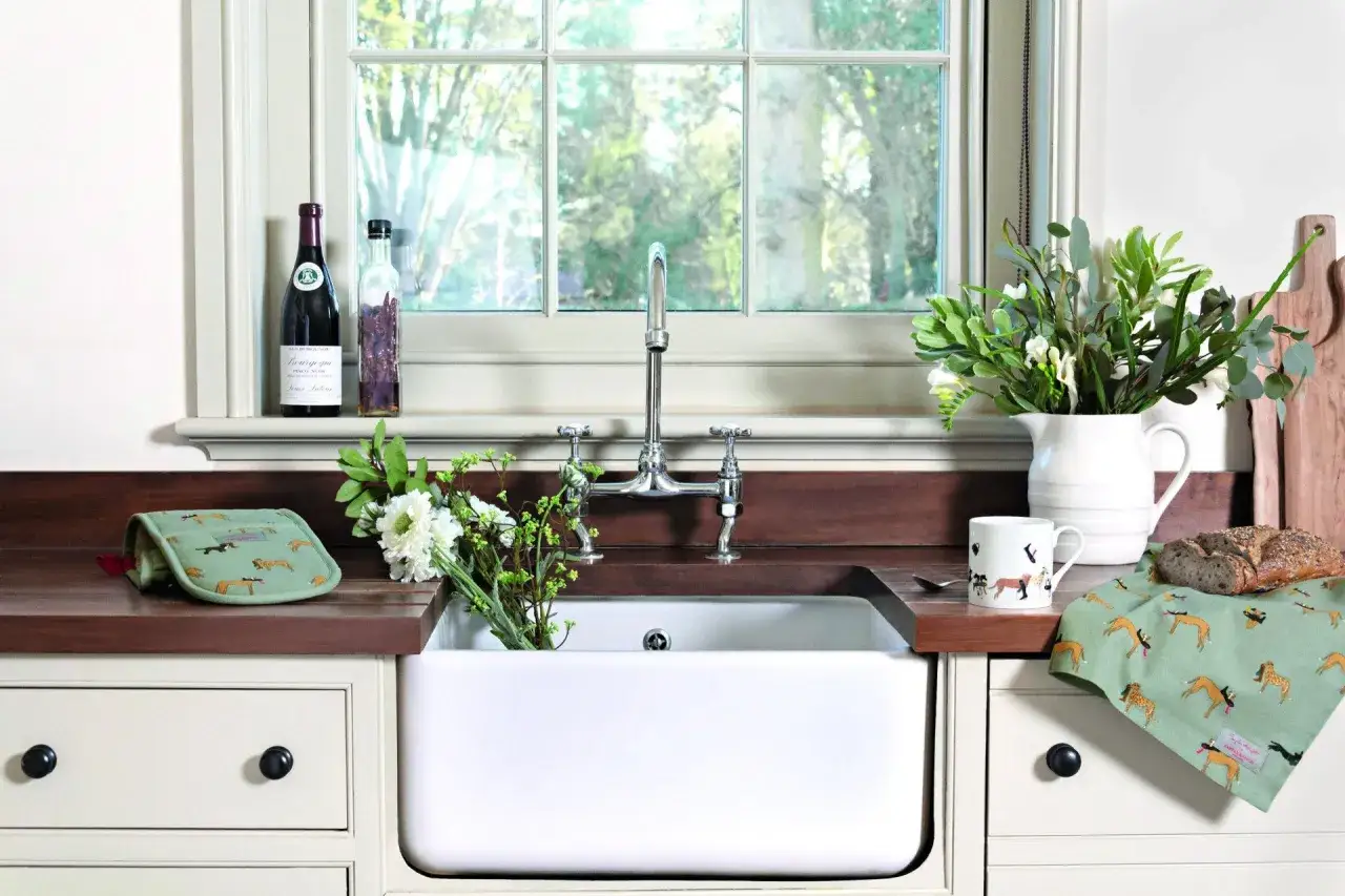 Uroczy parapet w kuchni z butelką wina, kwiatami, kubkiem i ściereczką z psami.