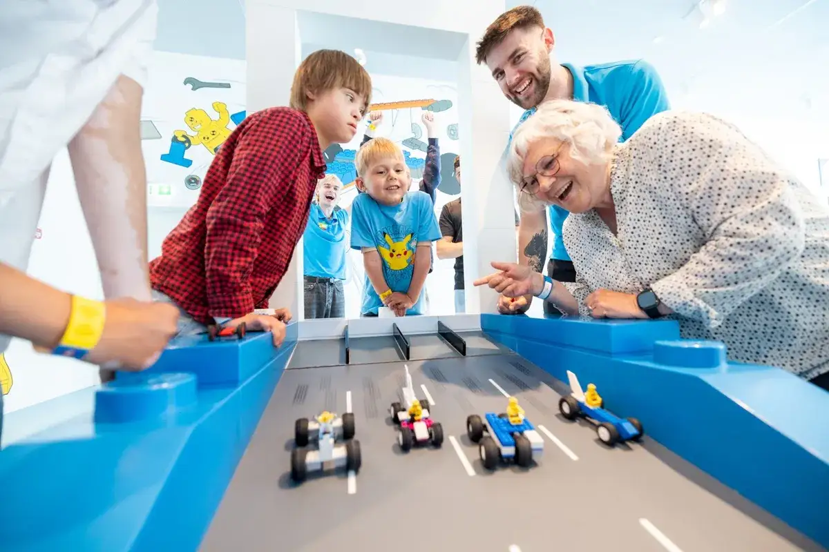 Rodzina śmieje się, grając w wyścigi samochodzików z klocków Lego w Billund.