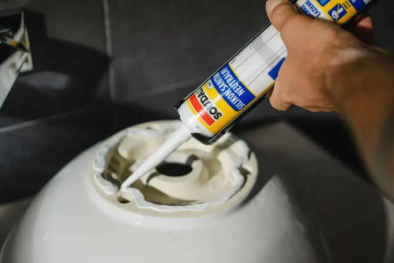 Nakładanie silikonu sanitarnego na umywalkę. Czas schnięcia akrylu jest kluczowy dla trwałości fugi.