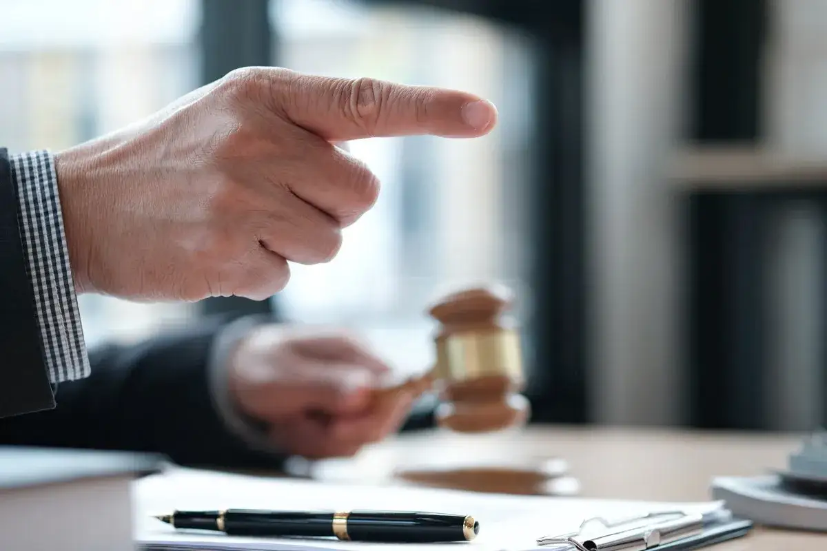 Sądowy młotek i wskazujący palec. Czy komornik może zająć zasiłek rehabilitacyjny? Pytanie o ochronę świadczeń.