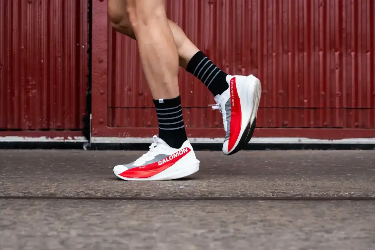 Biało-czerwone buty treningowo startowe Salomon Phantasm 2 na nogach biegacza, gotowe do pokonywania kilometrów.