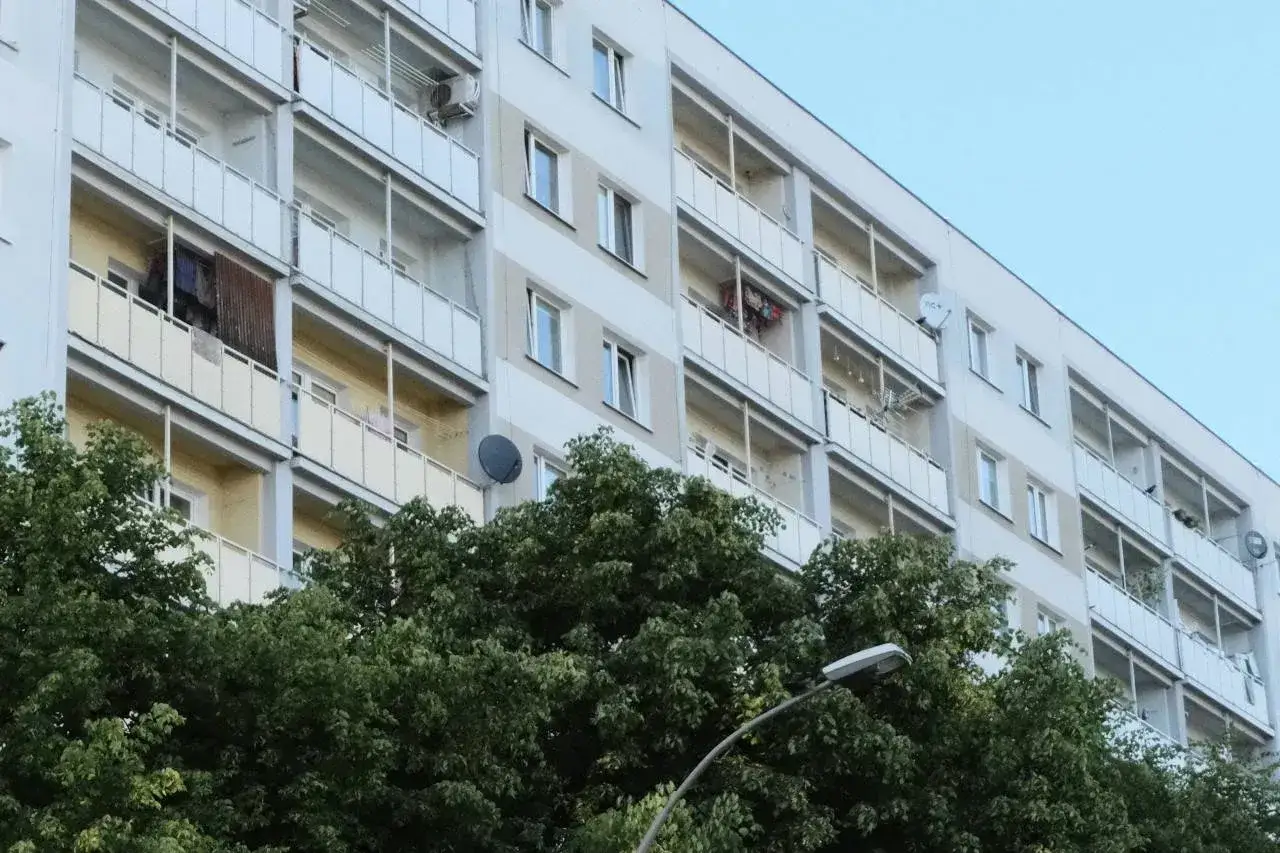 Blok mieszkalny z balkonami, drzewa i latarnia. Czy to zapowiedź, dlaczego od marca 2026 wspólnoty mieszkaniowe mogą nakładać wyższe kary za najem?