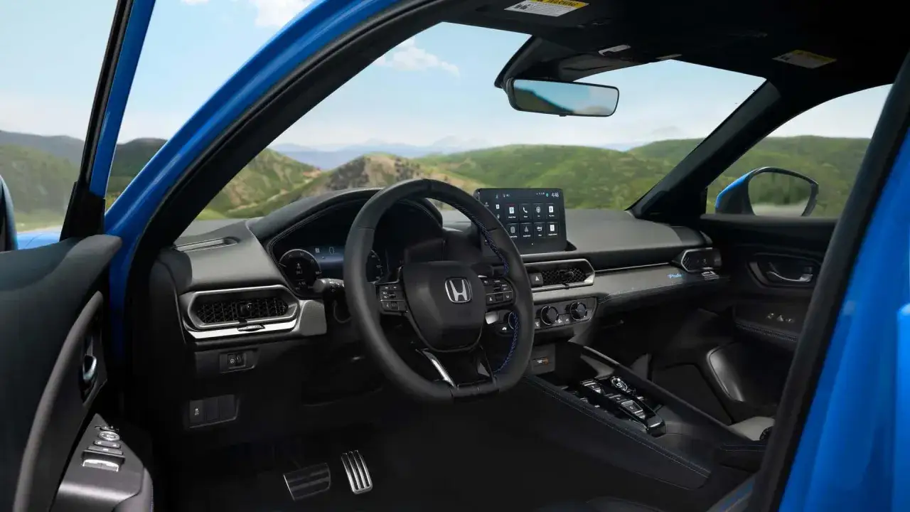 Wnętrze nowego Honda Prelude, z niebieskimi akcentami i nowoczesnym ekranem multimedialnym, gotowe na podróż przez malownicze krajobrazy.