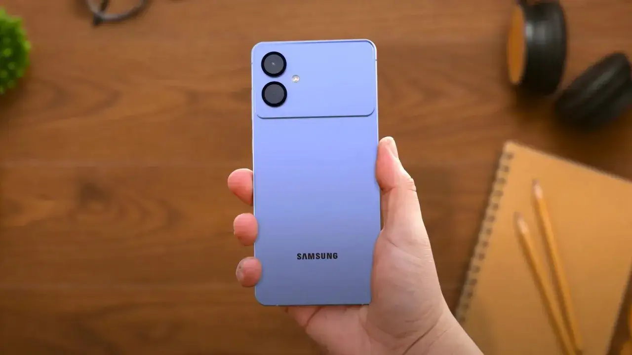 Fioletowy Samsung S26 premiera, z podwójnym aparatem i błyskiem, trzymany w dłoni na drewnianym tle.
