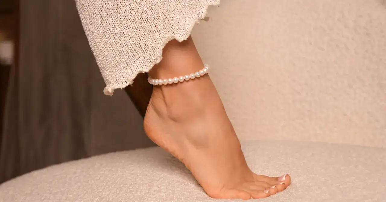 Delikatna bransoletka z pereł na prawej nodze, podkreślająca subtelność. Co oznacza bransoletka na prawej nodze? Symbol elegancji i kobiecości.