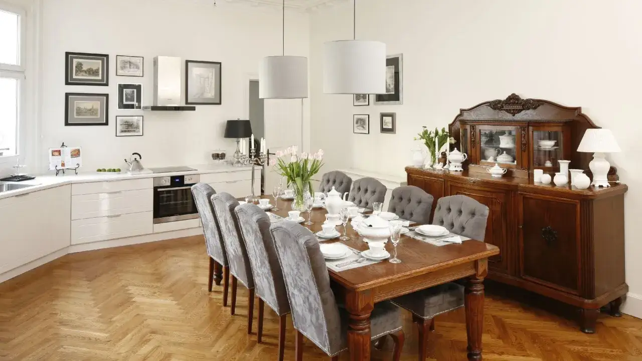 Elegancka jadalnia z drewnianym stołem i szarymi krzesłami. Jak wkomponować stary kredens? Ten zabytkowy mebel stanowi centralny punkt pomieszczenia, dodając mu charakteru i historii.