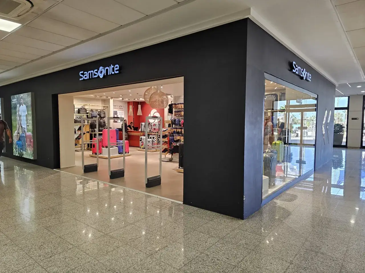 Sklep Samsonite na lotnisku Malta. W witrynie i wnętrzu sklepu widoczne są walizki i torby.
