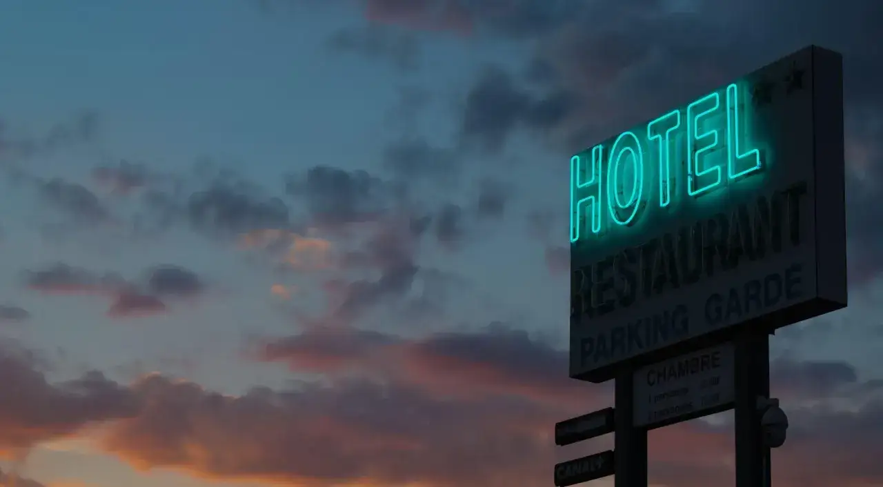 Neonowy szyld hotelu i restauracji na tle zachodzącego słońca. Idealne miejsce, gdzie reklamować noclegi, by przyciągnąć podróżnych.