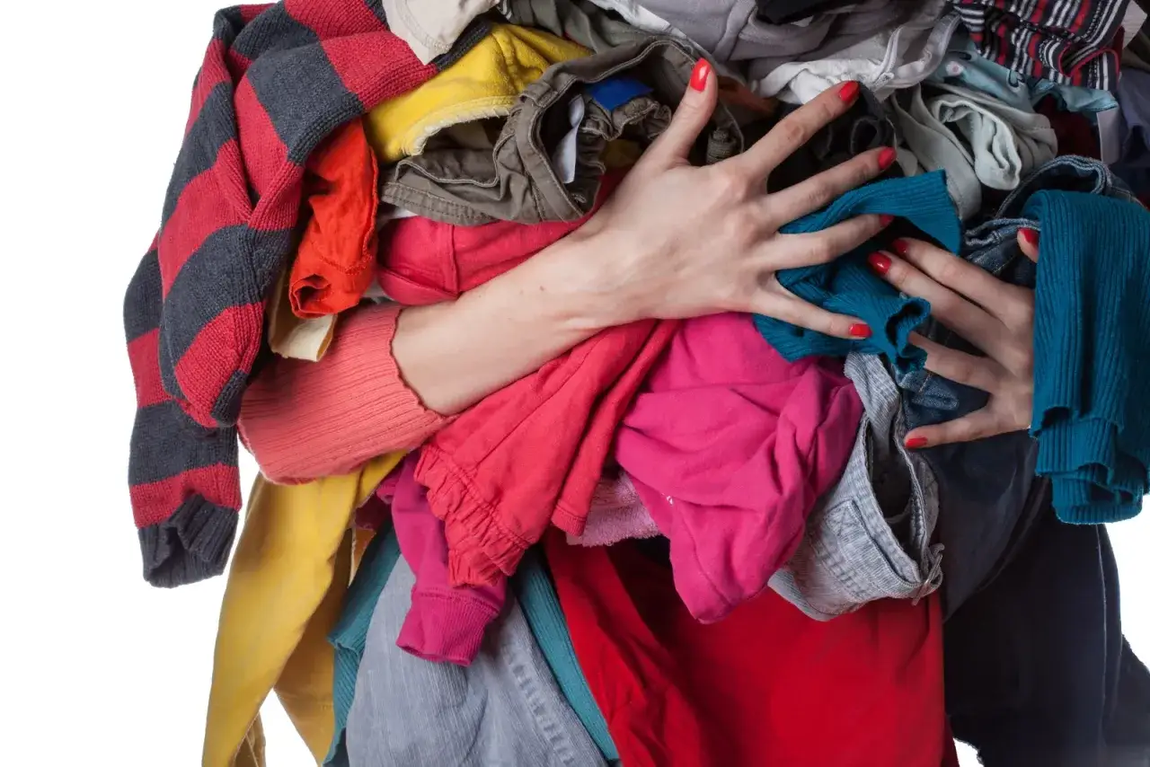 Stare ubrania w rękach. Zastanawiasz się, gdzie wyrzucić stare ubrania? Ta sterta kolorowych ubrań czeka na recykling.