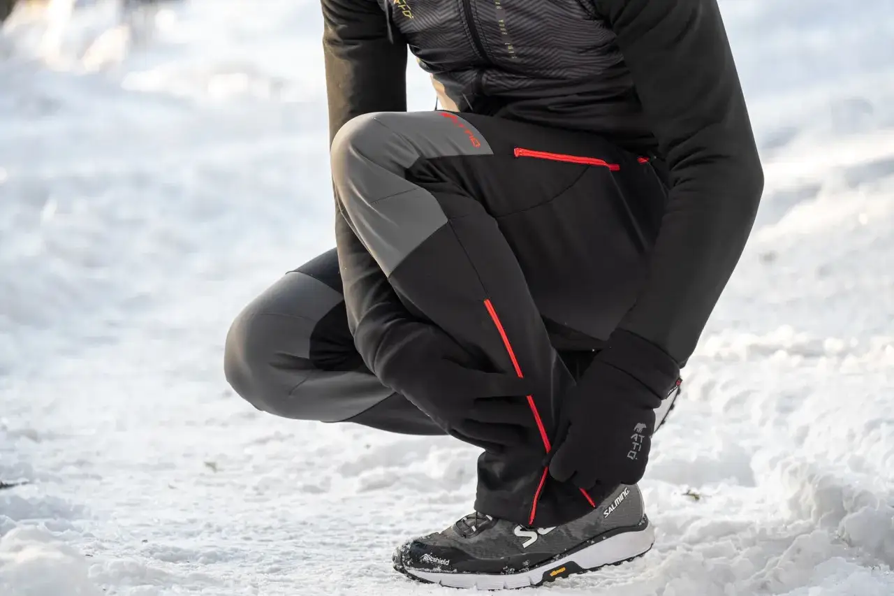 Idealne spodnie w g&oacute;ry zimą: czarne, z szarymi wstawkami i czerwonymi zamkami, zapewniające komfort i ciepło podczas zimowych wędr&oacute;wek.