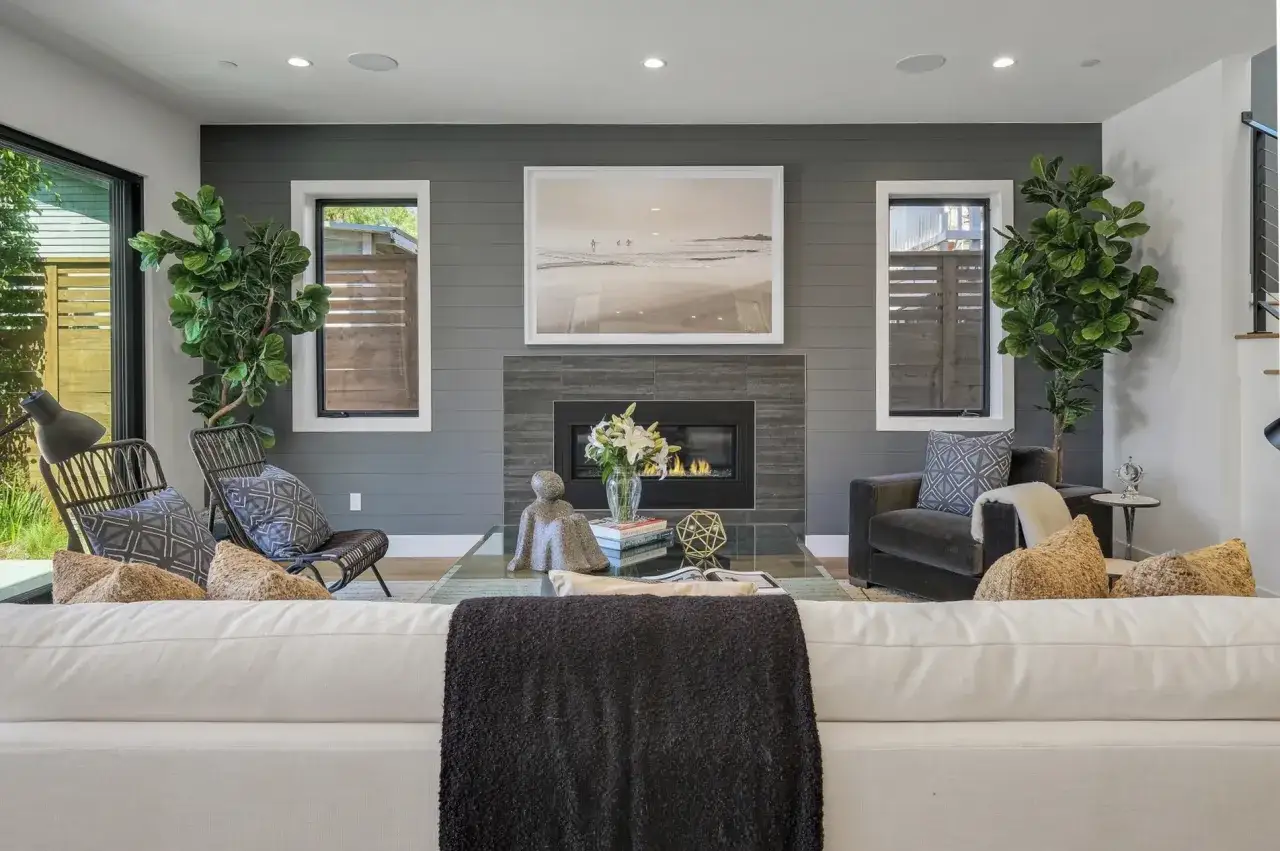 Modne kolory ścian galeria zdjęć: szara ściana z kominkiem, obraz plaży, rośliny, meble.