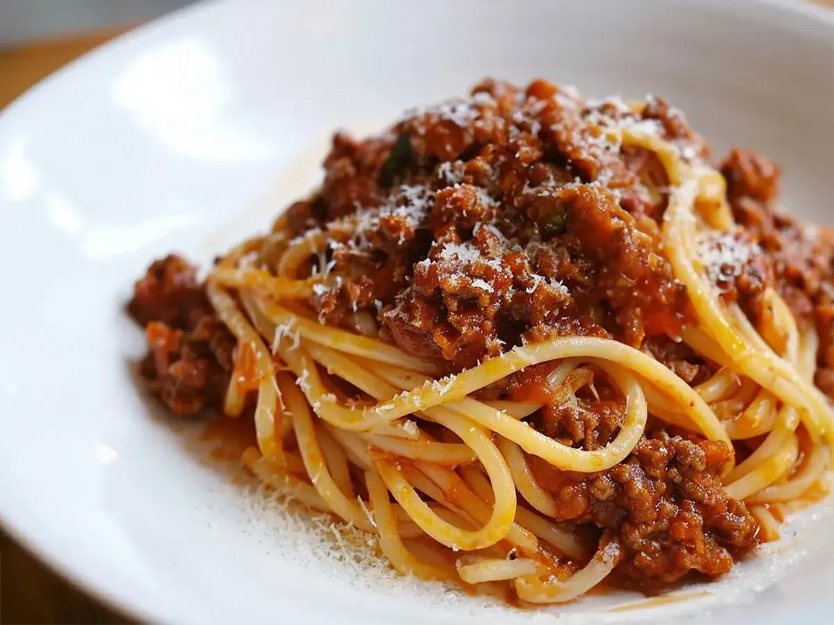 Pyszne spaghetti bolognese z passaty, obficie posypane parmezanem. Klasyka włoskiej kuchni na talerzu.