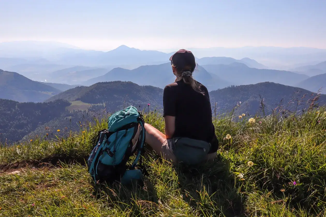 Widok na Małą Fatrę z plecakiem i turystką odpoczywającą na szczycie.