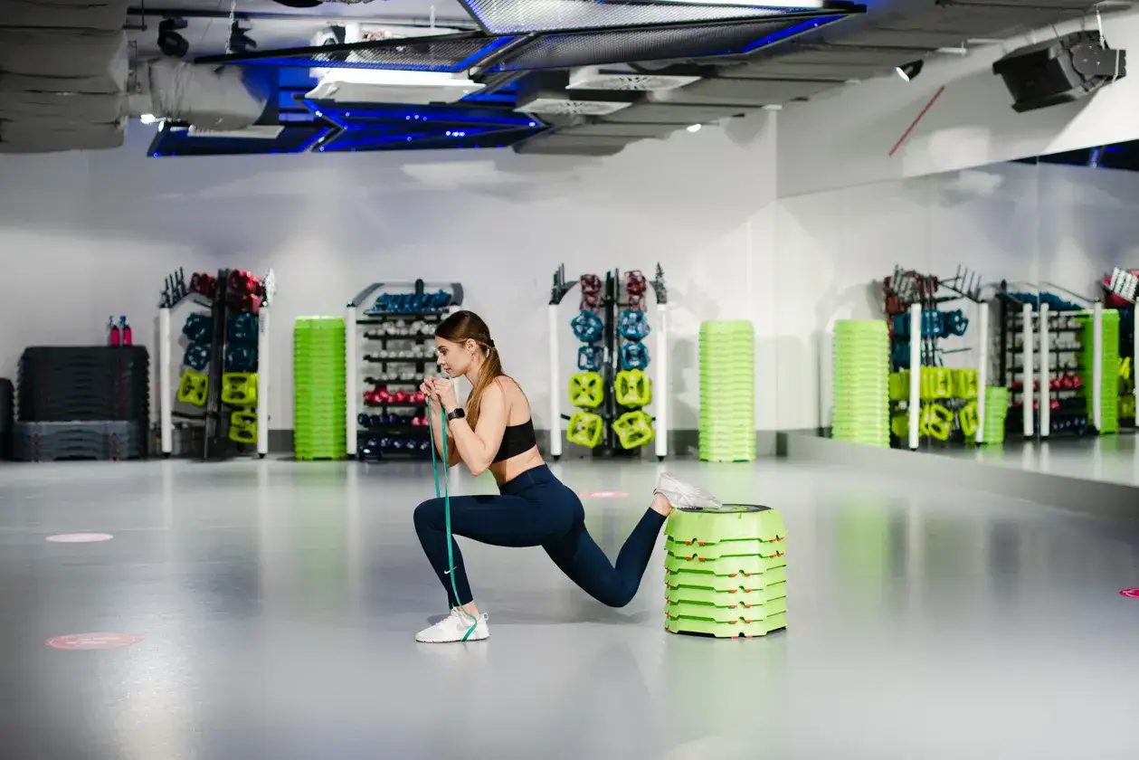 kobieta ćwicząca z gumą oporową na nogach, przysiad bułgarski