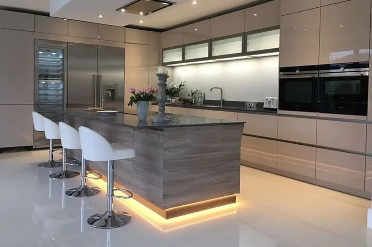 Nowoczesna kuchnia z wyspą, na której znajduje się oświetlenie cokołu w kuchni, tworzące ciepłą atmosferę.