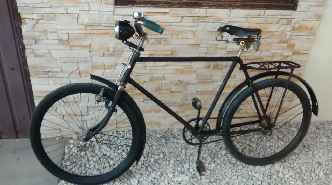 Czarny, zabytkowy rower stoi na żwirze. Zastanawiasz się, gdzie wyrzucić stary rower? Ten może trafić na złom lub do punktu zbiórki elektrośmieci.