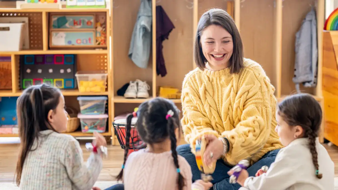 Dzieci bawiące się z uśmiechniętym nauczycielem w przedszkolu