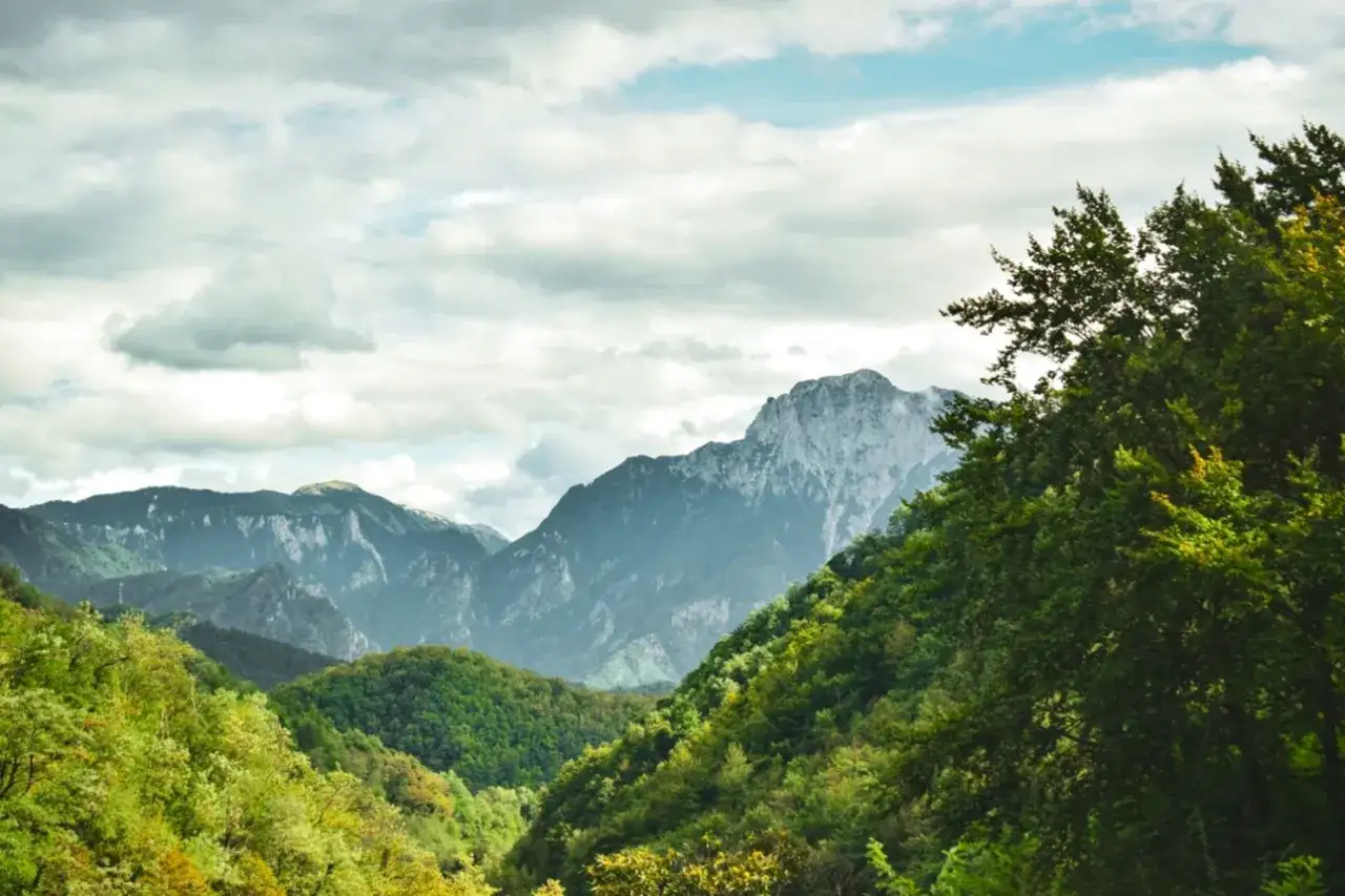 Górzyste krajobrazy podczas balkan trip. Zielone wzgórza i skaliste szczyty pod zachmurzonym niebem.