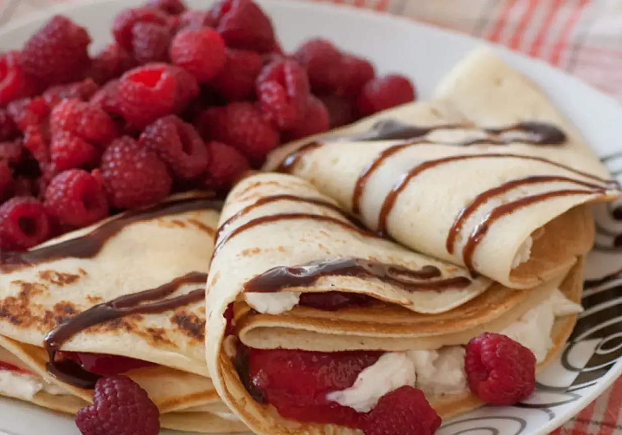 Pyszne naleśniki z serkiem mascarpone, polane czekoladą i podane z malinami. Idealne na deser!