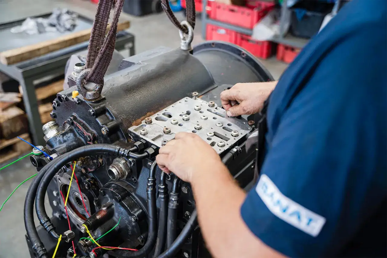 Mechanik pracuje nad złożonymi elementami skrzyni biegów, skupiając się na precyzyjnym montażu.