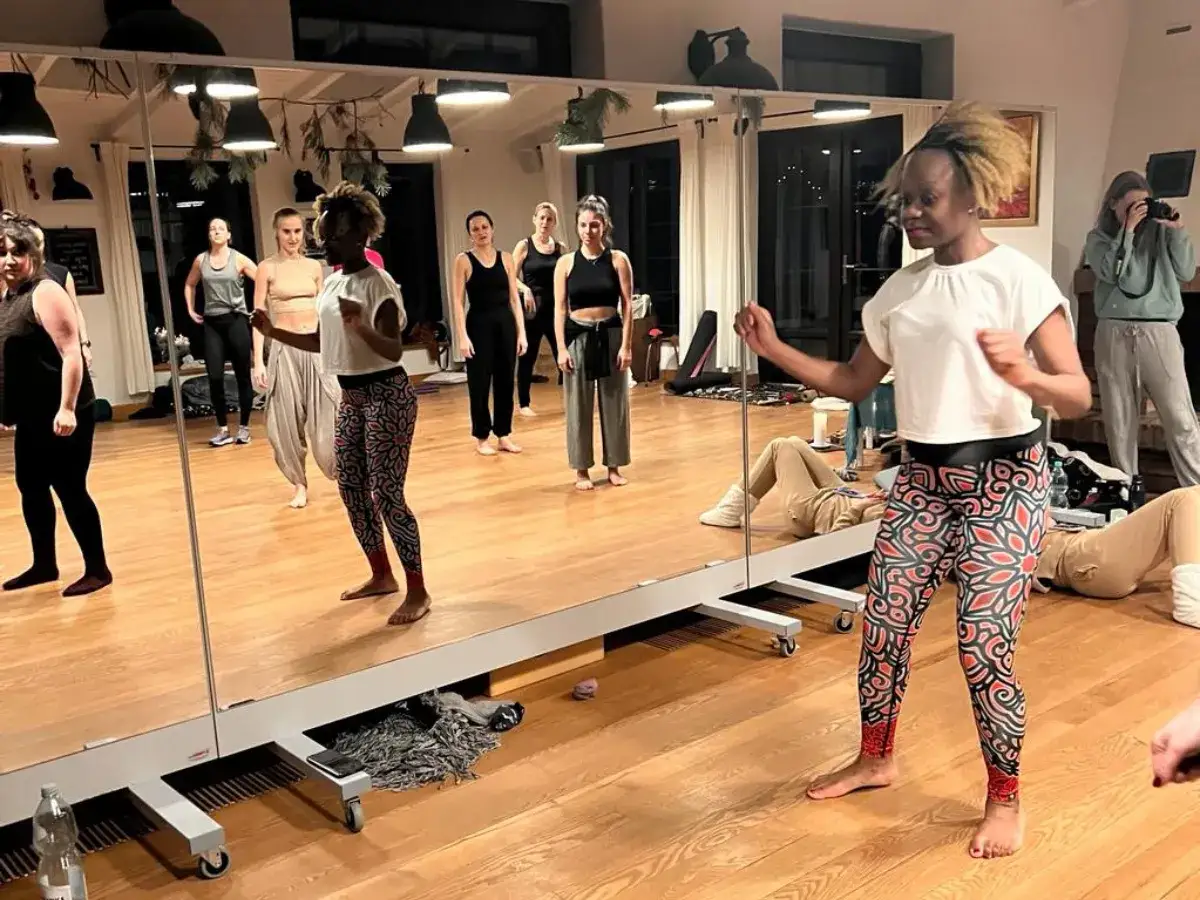 Grupa kobiet uczy się krok&oacute;w bachaty. Widać ich odbicia w lustrze, a instruktorka pokazuje podstawowe ruchy.