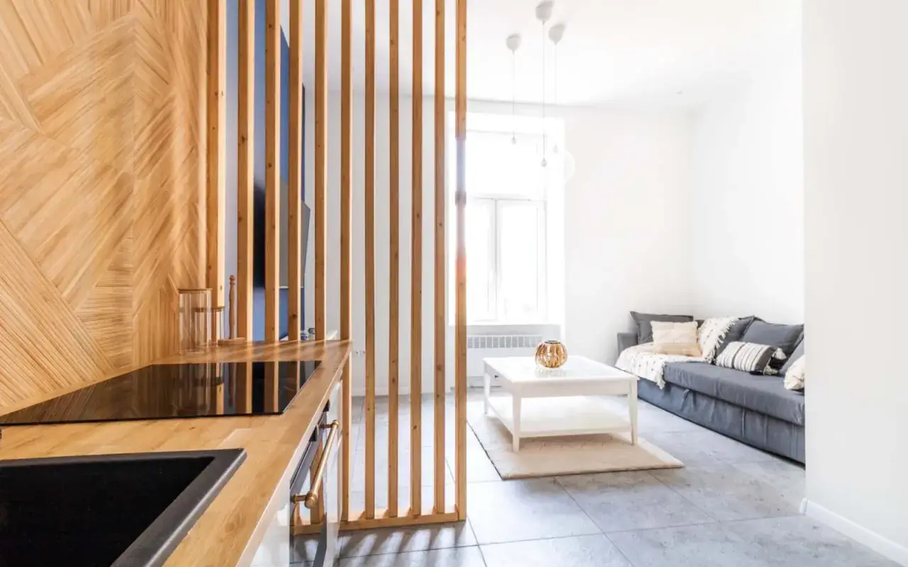 Nowoczesne wnętrze z drewnianą ścianką działową, idealne do aranżacji feng shui w mieszkaniu w bloku. Jasny salon z sofą i stolikiem.