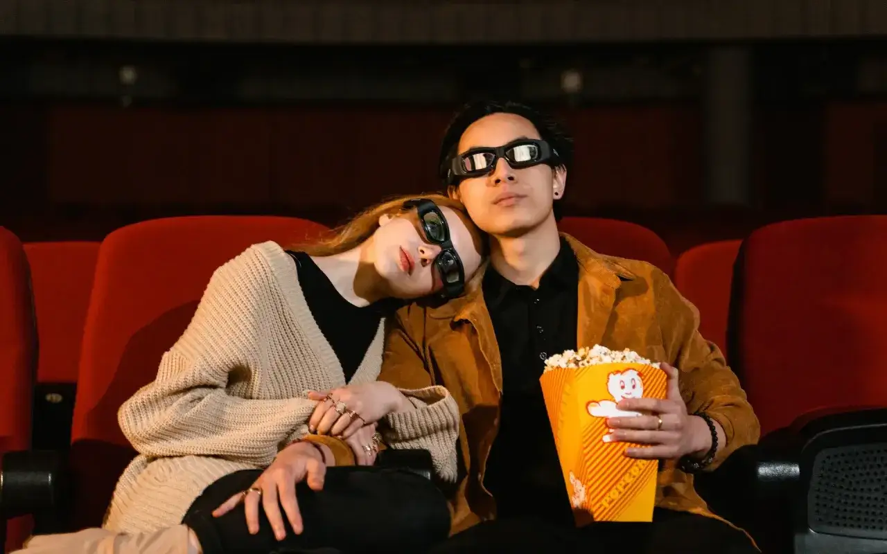 Para randkę w kinie, postaw na wygodę i styl. Ona w beżowym kardiganie, on w brązowej kurtce. Idealny strój na wspólne oglądanie filmu.