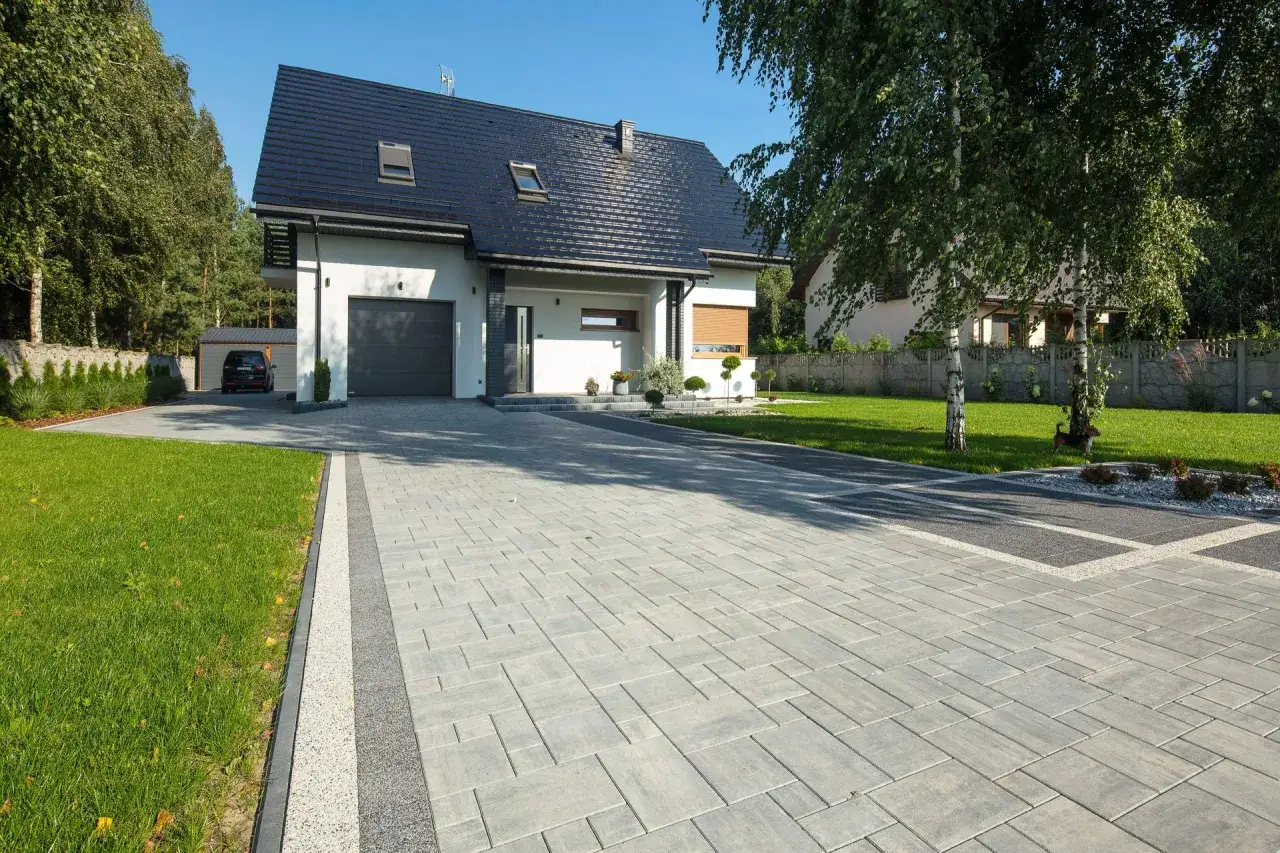 Nowoczesny dom z podjazdem z kostki brukowej. Sprawdź ceny układania kostki brukowej dla swojego ogrodu.