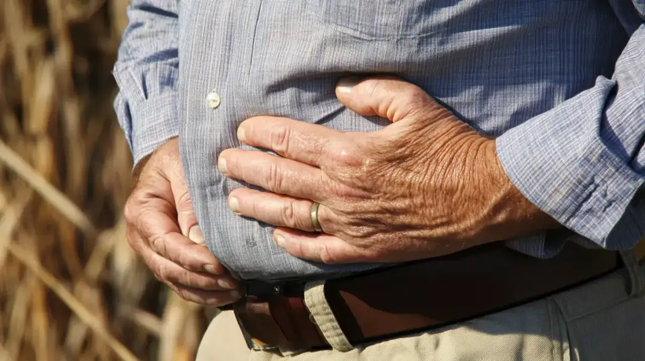 Mężczyzna trzyma się za brzuch, odczuwając dyskomfort w narządach po lewej stronie brzucha.
