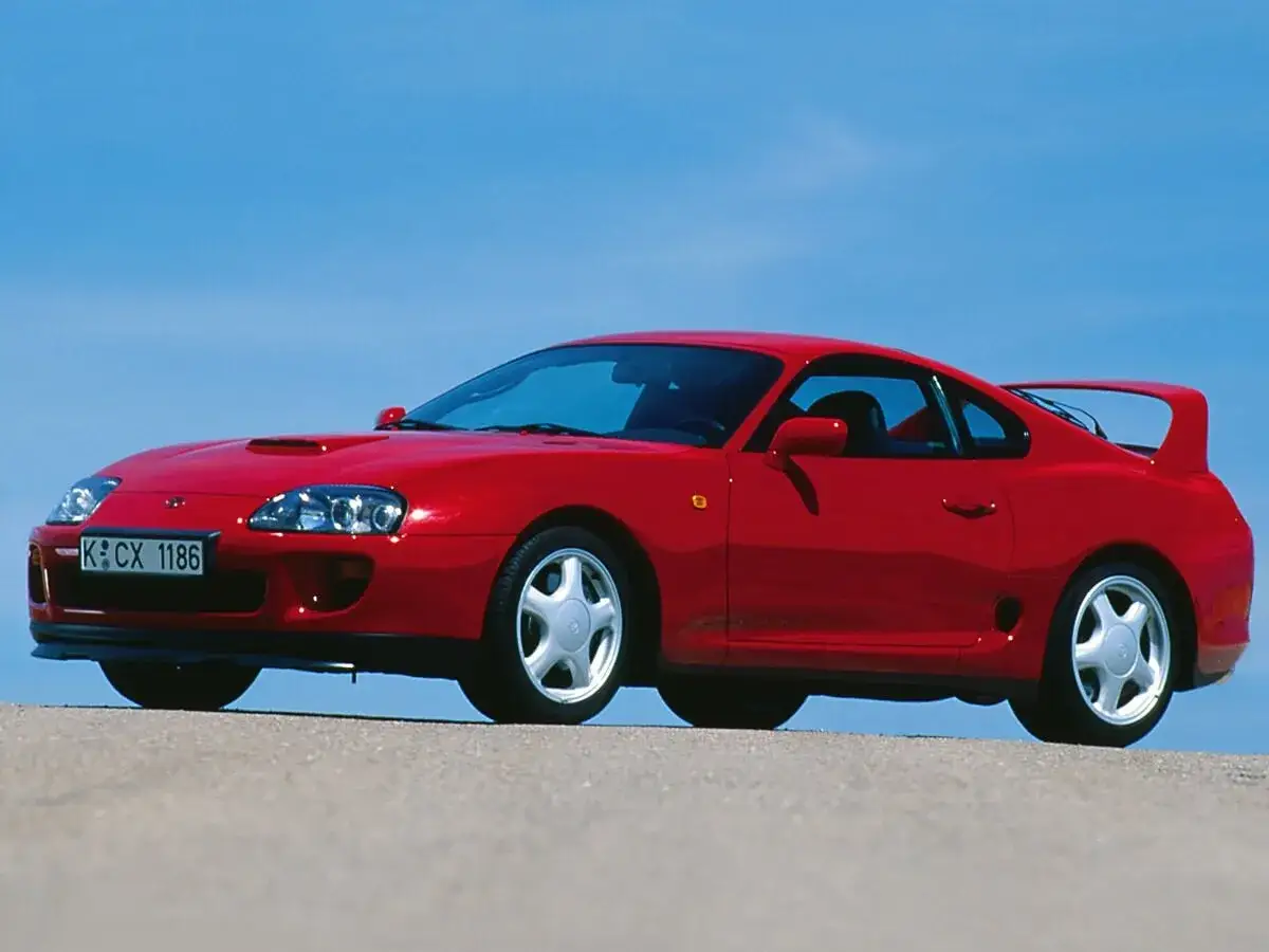 Czerwona Toyota Supra z charakterystycznym spojlerem, zapytanie o to, toyota supra ile ma koni, na tle błękitnego nieba.