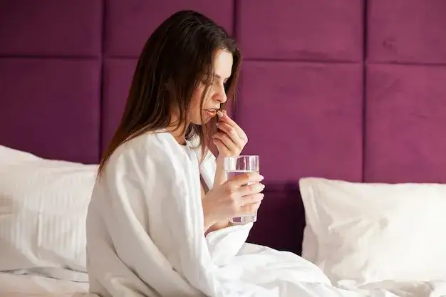 Kobieta pijąca wodę z tabletką rano