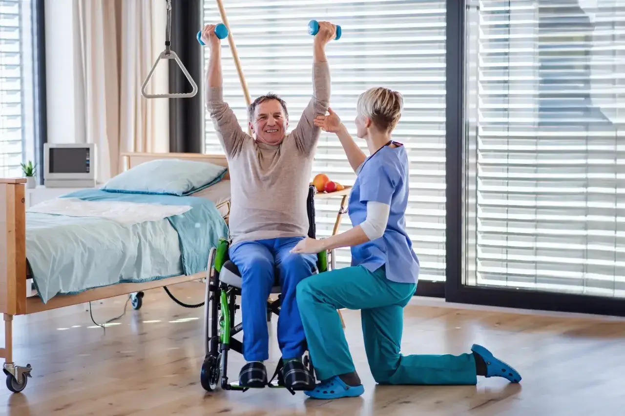 Starszy mężczyzna w wózku ćwiczy z hantlami pod okiem fizjoterapeutki. Czy rehabilitacje można odliczyć od podatku?