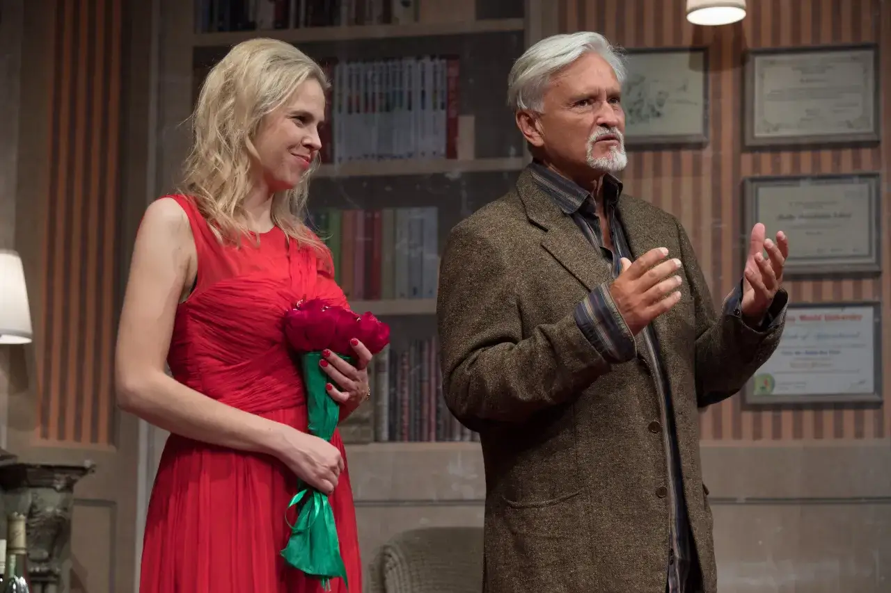 Kobieta w czerwonej sukni z bukietem i mężczyzna w tweedowej marynarce podczas spektaklu edukacja rity.