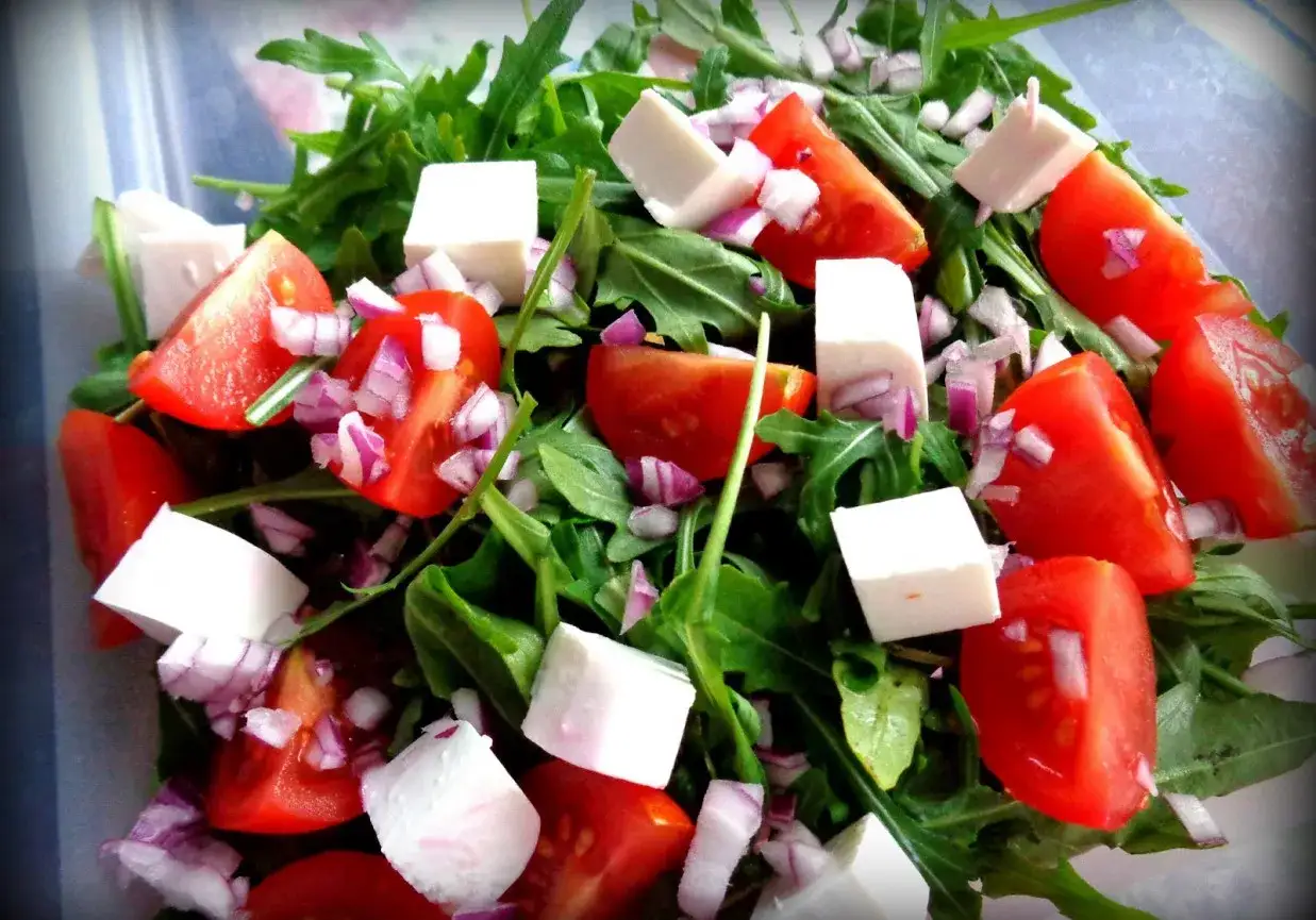 Sałatka z rukolą, fetą, pomidorkami koktajlowymi i czerwoną cebulą.