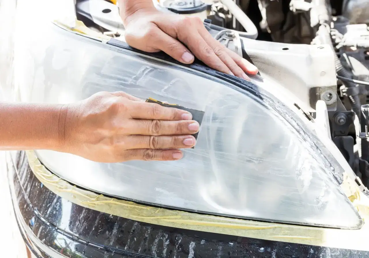 Ręce polerują reflektor papierem ściernym. To kluczowy etap, by dobrać odpowiedni papier do polerowania lamp i przywr&oacute;cić im blask.