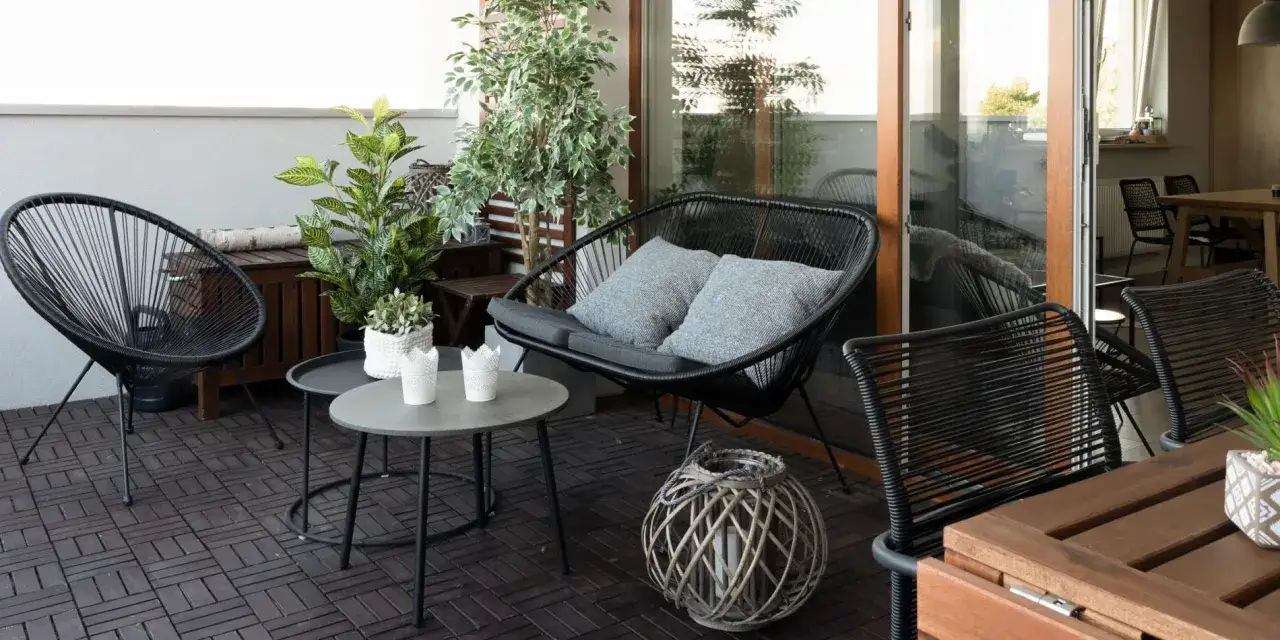 Nowoczesny balkon z czarnymi meblami i roślinami. Idealne miejsce na relaks, jak przedłużyć balkon betonowy, by stworzyć taką oazę.