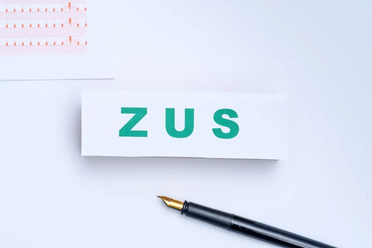 ZUS. Litery na białym tle, obok pióro i formularz. To może być kod literowy zwolnienia.