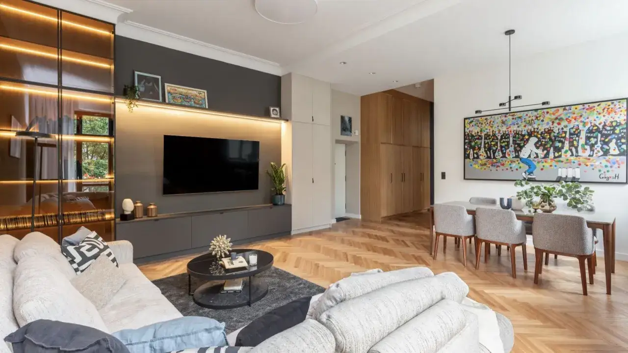 Nowoczesny salon z podświetlaną szafką RTV i kolorowym obrazem nad stołem. Inspiracja, jak ozdobić ścianę w pokoju.