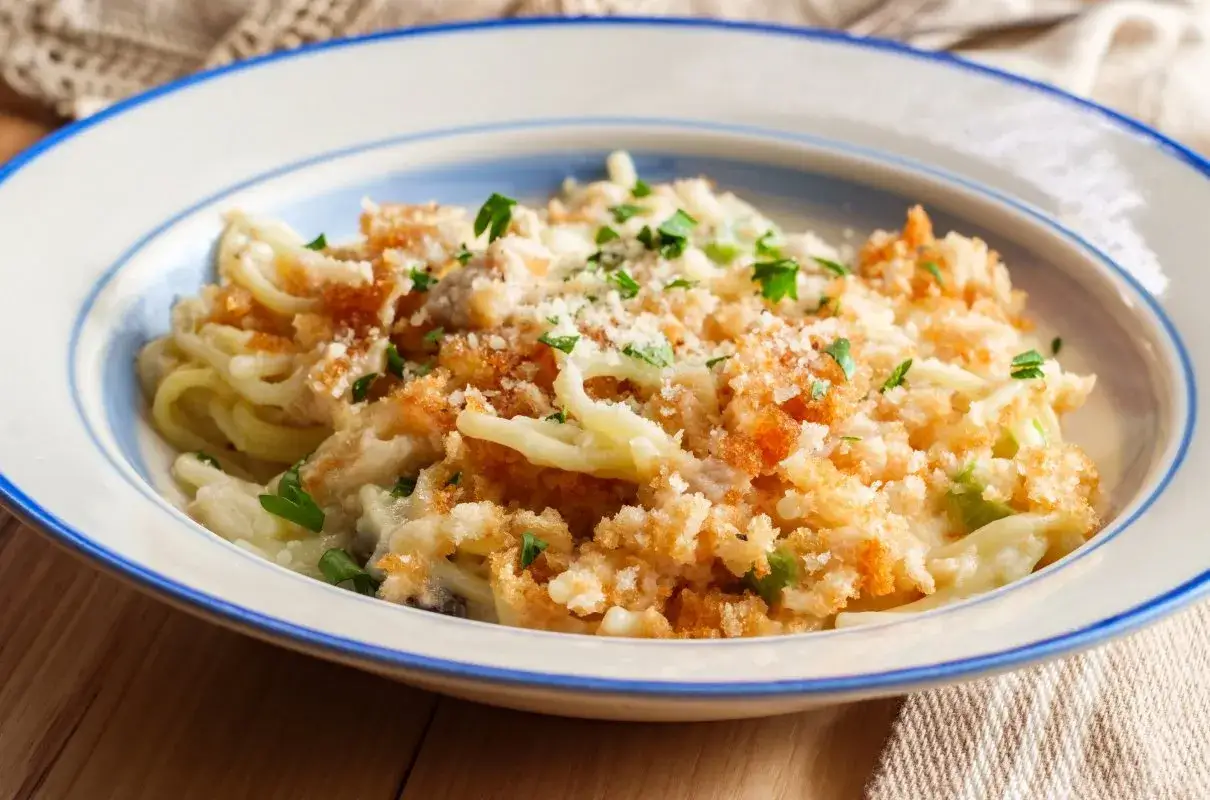 Pyszne spaghetti z kurczakiem w kremowym sosie alfredo, posypane chrupiącą panierką i natką pietruszki. Idealny przepis na chicken alfredo.