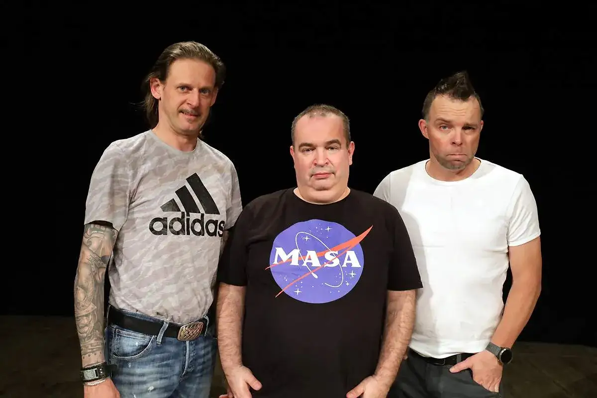 Trzech mężczyzn, w tym Marcin W&oacute;jcik z kabaretu, pozuje do zdjęcia. Jeden w koszulce z logo NASA.