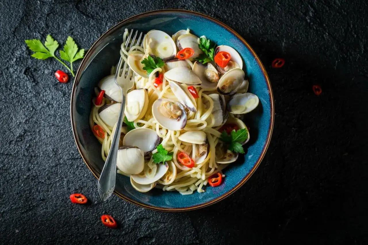Pyszne Spaghetti con le Vongole przepis. Aromatyczny makaron z małżami, czosnkiem i chili, udekorowany natką pietruszki.