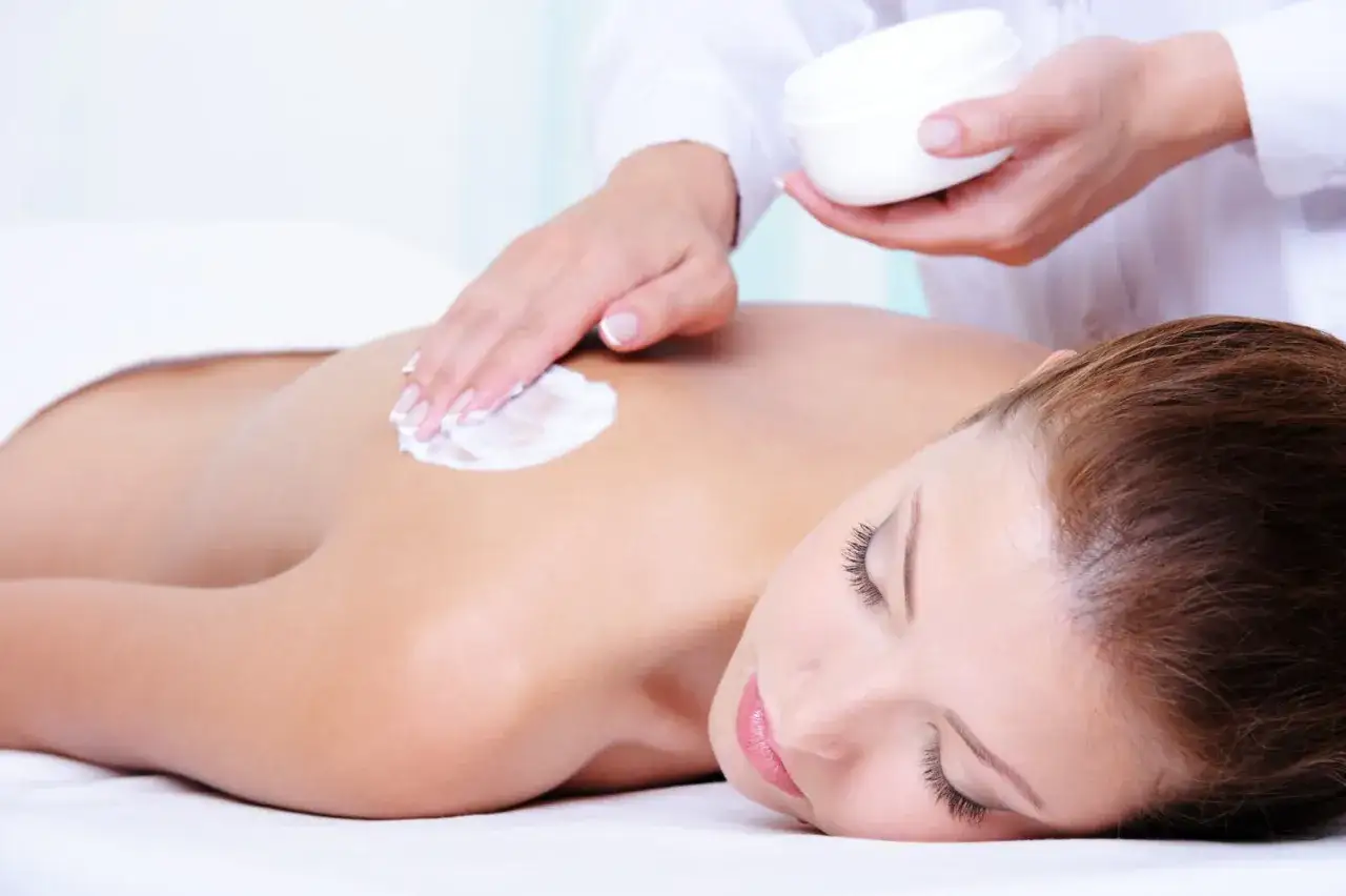 Kobieta wykonująca peeling ciała przed depilacją