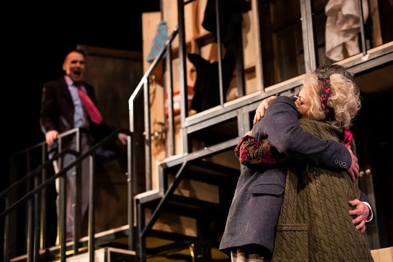 Dwie osoby obejmują się na scenie. W tle mężczyzna krzyczy. To scena z Teatru Osterwy, czego nie widać na pierwszym planie.