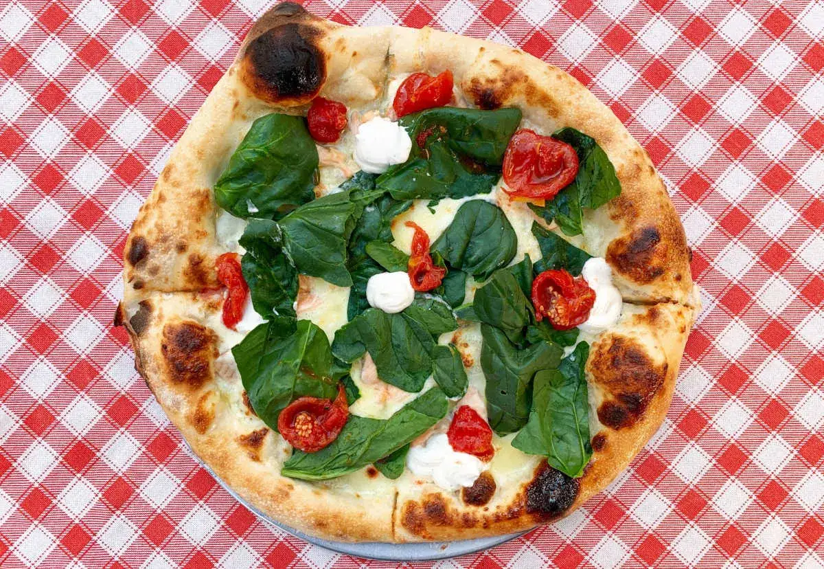 Pyszna pizza ze szpinakiem, pomidorkami i mozzarellą, jak z pizzeri. Idealny przepis na domową ucztę.