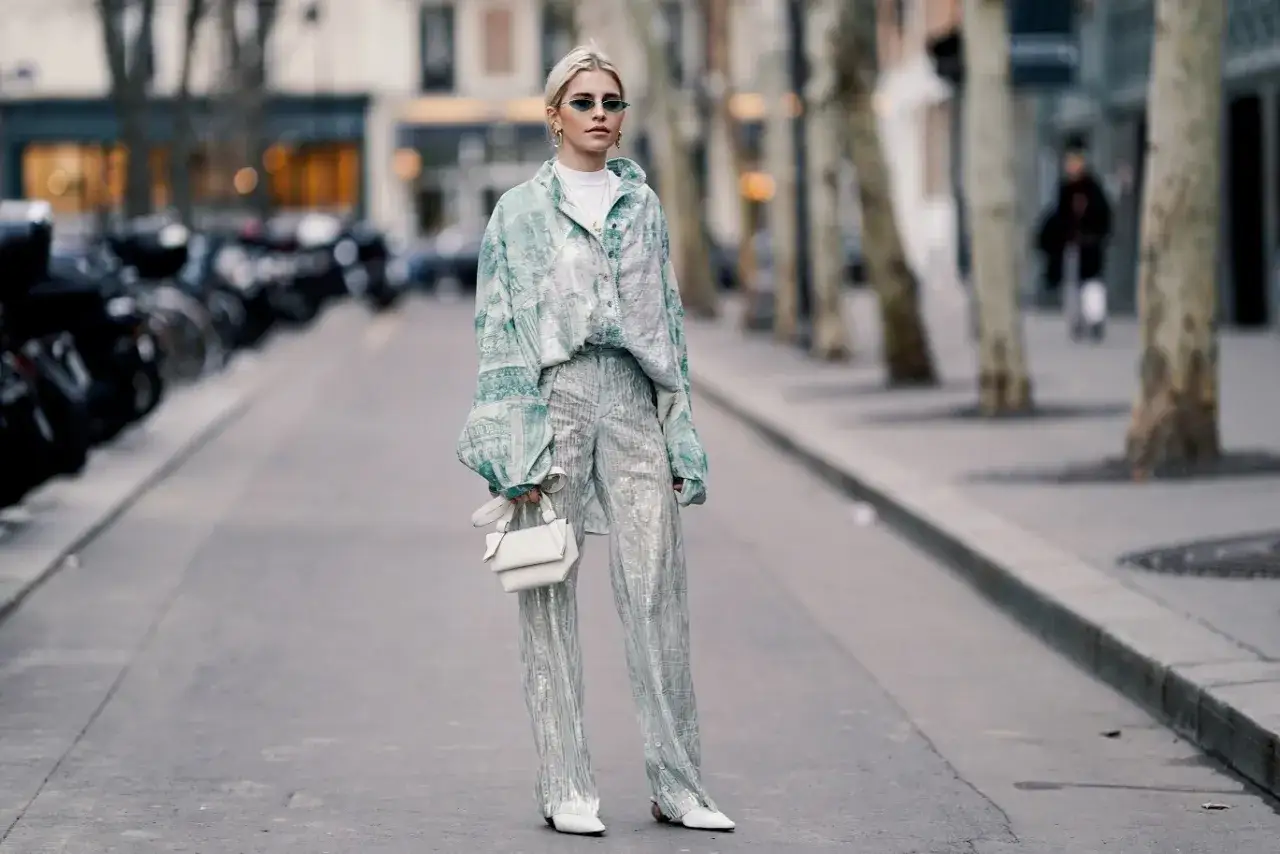 Kobieta w błyszczących, srebrnych spodniach i wzorzystej koszuli na ulicy. Czy cekiny są modne? Ten look sugeruje, że tak!