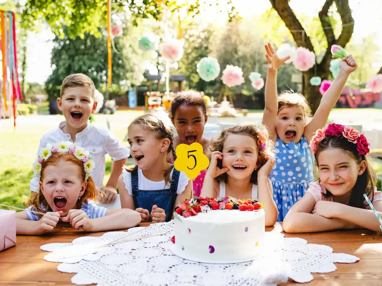 Radosne dzieci świętują 5. urodziny przy torcie i ozdobach. Wesołe zabawy na urodziny w ogrodzie.